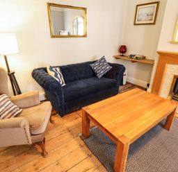A living room with a blue sofa and wooden coffee table at Maples in Hunstanton