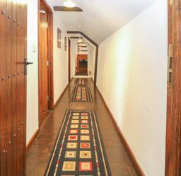 A hallway with wooden doors rugs on the floor and white walls at The Old Barn in Walcott