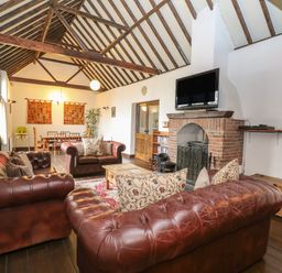 A living room with leather sofas a brick fireplace and a dining table at The Old Barn in Walcott