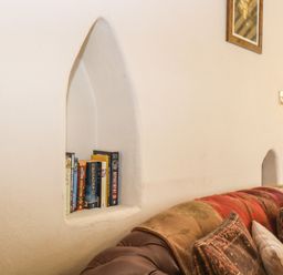 A living room wall with a built-in niche holding books above a sofa with cushions at The Old Barn in Walcott