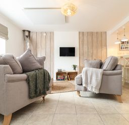 A living room with two gray sofas and a wall-mounted TV at The Old Post Office in Porthleven