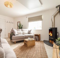 A living room with two sofas a wooden crate table a fireplace and a TV at The Old Post Office in Porthleven
