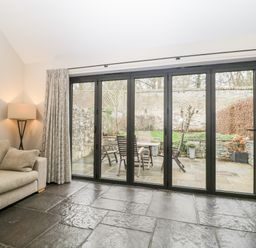 A living room with a beige sofa lamp and glass sliding doors leading to a patio at Willow Barn in Shapwick