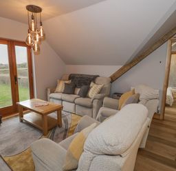 A living room with sofas a wooden coffee table and glass doors leading outside at Hallgarth Farm Holiday Lodge in Peopleton