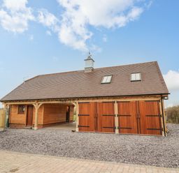 A detached wooden garage with three large doors and two skylights at Hallgarth Farm Holiday Lodge in Peopleton