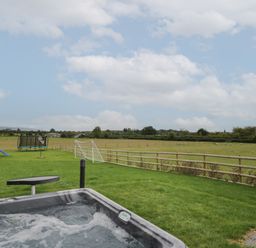 A backyard with a hot tub a small table a play structure a trampoline a soccer goal and fields at Hallgarth Farm Holiday Lodge in Peopleton