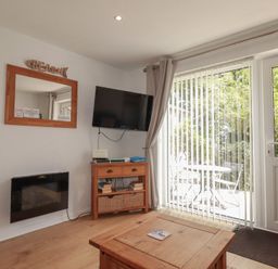 A living room with a television and sliding door at 49 Atlantic Reach in Newquay