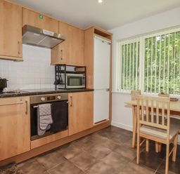 A kitchen with cabinets, oven, microwave, and dining table at 49 Atlantic Reach in Newquay