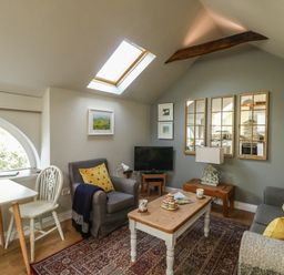 A living room with a skylight, armchairs, a coffee table, a television, and mirrors at Little Brook in Nottington near Weymouth