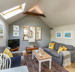 A sitting area with two gray sofas a wooden coffee table a small television and skylight at Little Brook in Nottington near Weymouth
