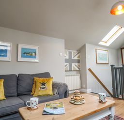 A living room with grey sofa with bee cushions and a wooden coffee table with muffins and cups at Little Brook Nottington near Weymouth