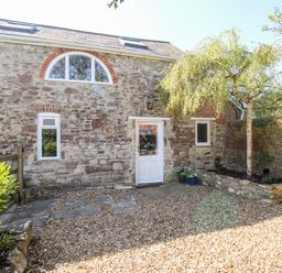 Exterior view of a stone cottage with gravel courtyard and small tree at Little Brook Nottington near Weymouth
