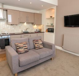 A kitchen with cabinets couch and a wall mounted tv at 4 Dartview in Dartmouth