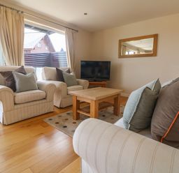 A living room with two armchairs a sofa a wooden coffee table a television and a mirror at Redwood Retallack in Retallack near St Columb Major