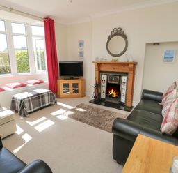 A living room with a fireplace a television sofas and a window seat at The Nook in Benllech