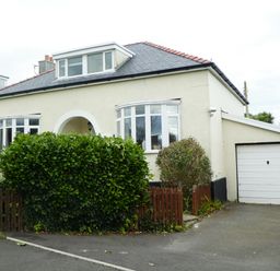 A detached house with a driveway garage and front garden with shrubs at The Nook in Benllech