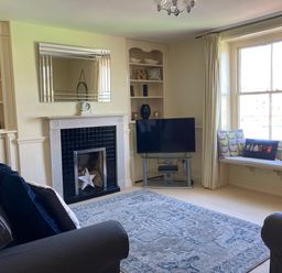 A living room with a fireplace a television and a window seat at Harbourside Cottage Brewers Quay Harbour