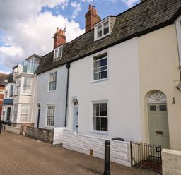A street view of terraced houses with chimneys along a paved road at Harbourside Cottage in Brewers Quay Harbour