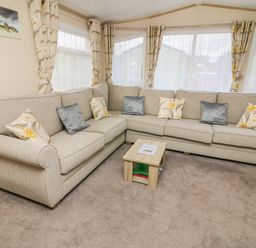 A living room with a large beige corner sofa and small wooden coffee table at 12A Borwick Lakes South Lakeland Leisure Village