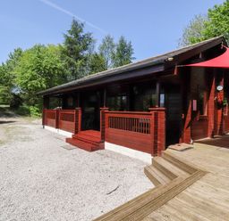 A wooden lodge with a red canopy and surrounding trees at Gisburn Forest Lodge in Tosside near Wigglesworth