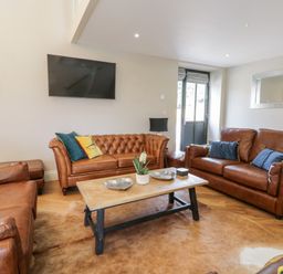 A living room with brown leather sofas a wooden coffee table and a wall-mounted TV at Pheasant's Roost in Lelley near Burton Pidsea