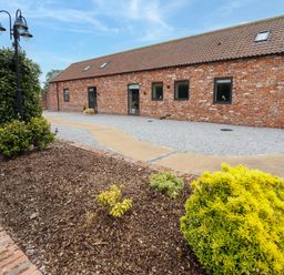 A brick building with a tiled roof and small shrubs in a garden near a gravel path at Pheasant's Roost in Lelley near Burton Pidsea