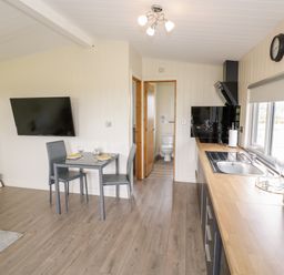 A kitchen and dining area with a table set for two and a view of a bathroom at Cotswold View 3 in Bretforton near Evesham