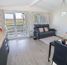 A living room with a kitchen counter, sofa, dining table, and outdoor patio at Cotswold View 4 in Bretforton near Evesham