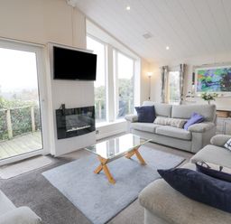 A living room with sofas coffee table wall-mounted TV and fireplace at Oyster Bay Lodge in Dalbeattie