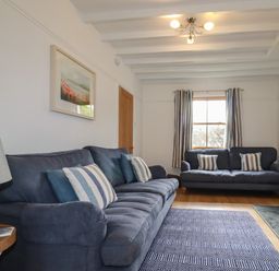 A sitting room with two blue sofas a patterned rug a lamp and a fireplace at Tresawle in Crantock