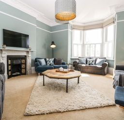 A living room with sofas around a wooden coffee table on a rug at Bay Tree House in Seaton Devon