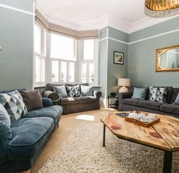 A living room with three sofas cushions a wooden coffee table a floor lamp and a table lamp by Bay Tree House in Seaton Devon