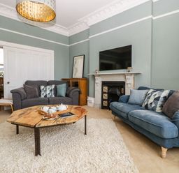 A living room with two sofas a wooden coffee table and a fireplace at Bay Tree House in Seaton Devon