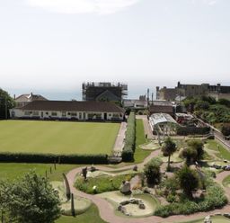 An outdoor area with a bowling green and mini golf course near buildings and the sea at Bay Tree House in Seaton Devon