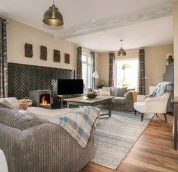 A living room with sofas a coffee table a fireplace and a television at Crantock Lodge in Crantock