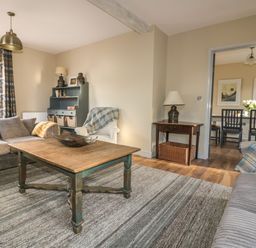 A living room with sofas table and cabinet open to dining area at Crantock Lodge in Crantock