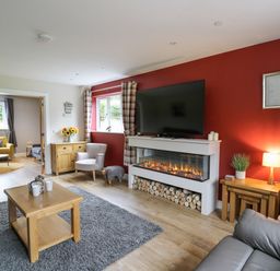 A living room with a fireplace television and wooden furniture at Talarddu Cottage in Builth Wells