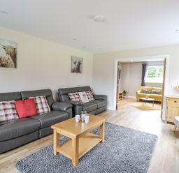 A living room with two black leather sofas a wooden coffee table and a grey rug at Talarddu Cottage in Builth Wells