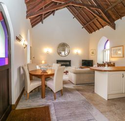 An open living space with a dining table and chairs a sofa a television and kitchen island at Frogwell Chapel in Frogwell near Callington
