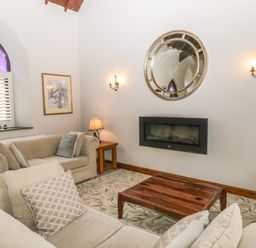 A living room with sofas wooden coffee table and wall-mounted fireplace at Frogwell Chapel in Frogwell near Callington