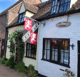 A view of King John's Cottages with flags and flowers in Tewkesbury