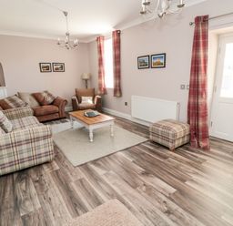 A living room with sofas armchair coffee table ottoman and framed pictures at Deanrise in Shilbottle near Alnwick