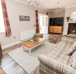 A living room with plaid sofa brown armchair coffee table and fireplace at Deanrise in Shilbottle near Alnwick