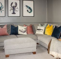 A grey sectional sofa with colorful cushions and framed sea creature prints on the wall at Ferrystone Kingswear near Dartmouth