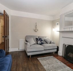A living room with two sofas a fireplace and a rug at Hunny Cottage in Hunstanton