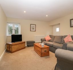 A sitting room with grey sofas wooden chests a television and framed pictures on the walls at Magnolia Barn in Mark
