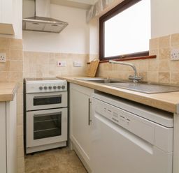 A kitchen corner with a stove a sink a dishwasher and tiled backsplash at The Stables in Crowcombe
