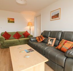 A living room with two sofas a coffee table and framed pictures on the walls at The Outlook in Crowcombe