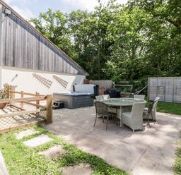 An outdoor patio area with a round glass table and chairs next to a modern two-story building at The Outlook in Crowcombe