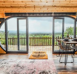A wooden interior room with large glass doors opening to a balcony and a dining table with chairs at Offas Dyke Escape in St Asaph